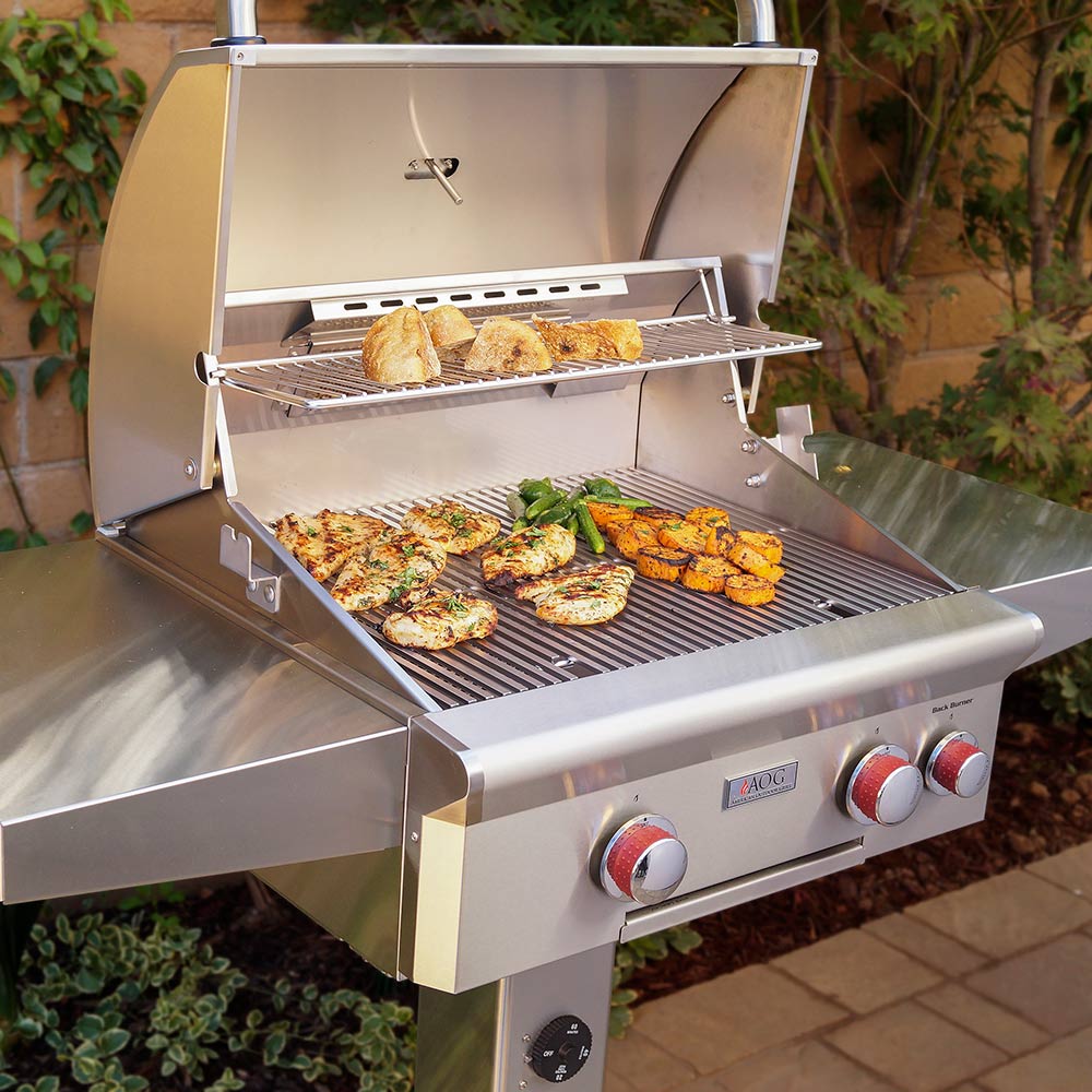 Open stainless gas grill with cooking grate, flame area, and grilled food