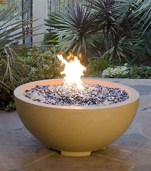 Round gas fire bowl with yellow finish and visible flames over fire bed