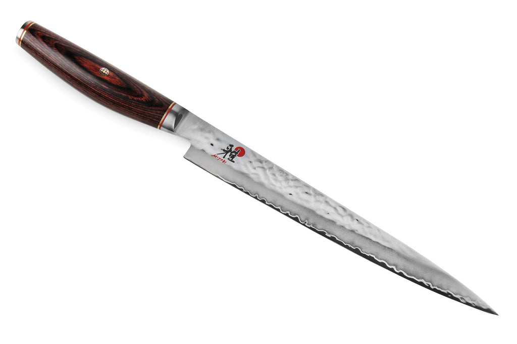 Chef slicing knife with dark wood handle and hammered steel blade, serrated