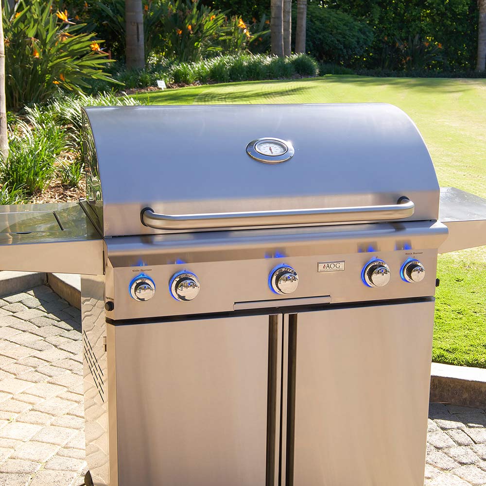 Stainless steel gas grill with domed lid and four front control knobs