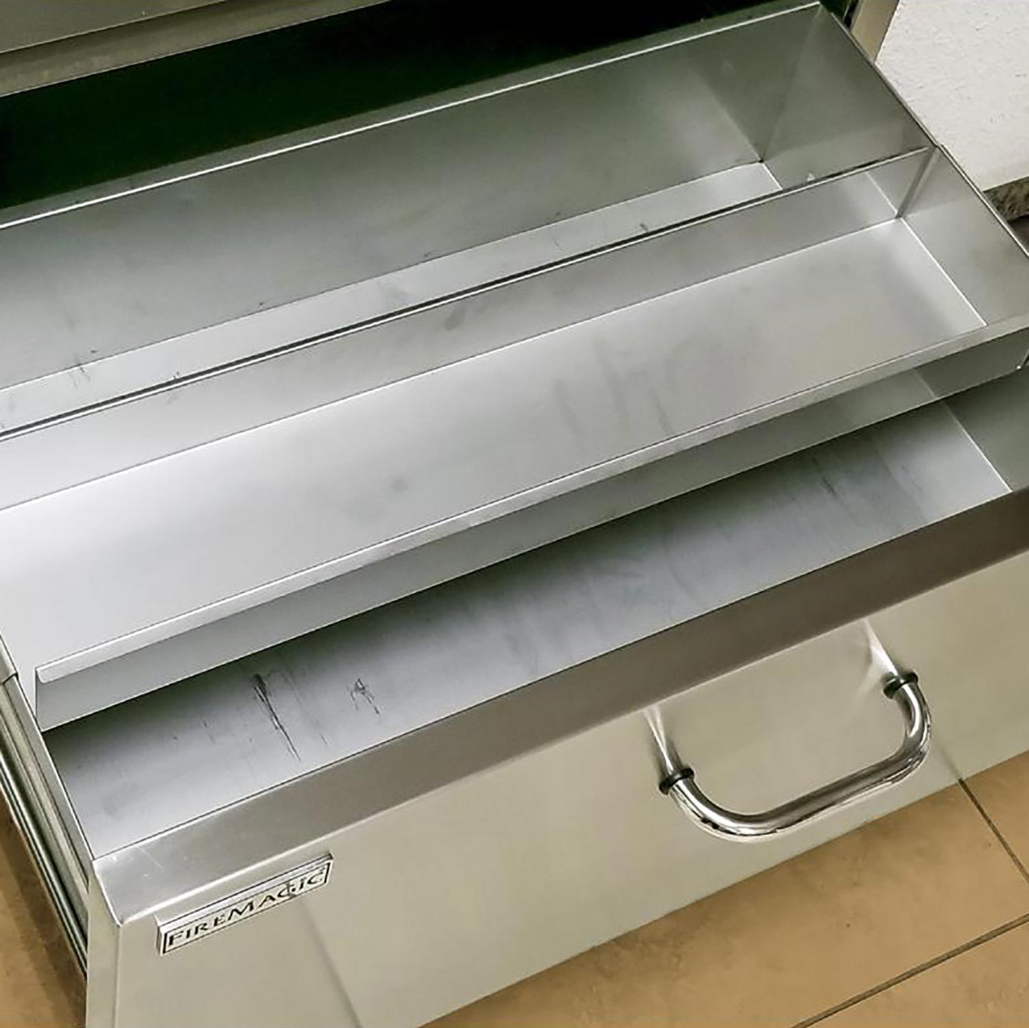 Fire Magic stainless drawer interior with curved pull handles and side label