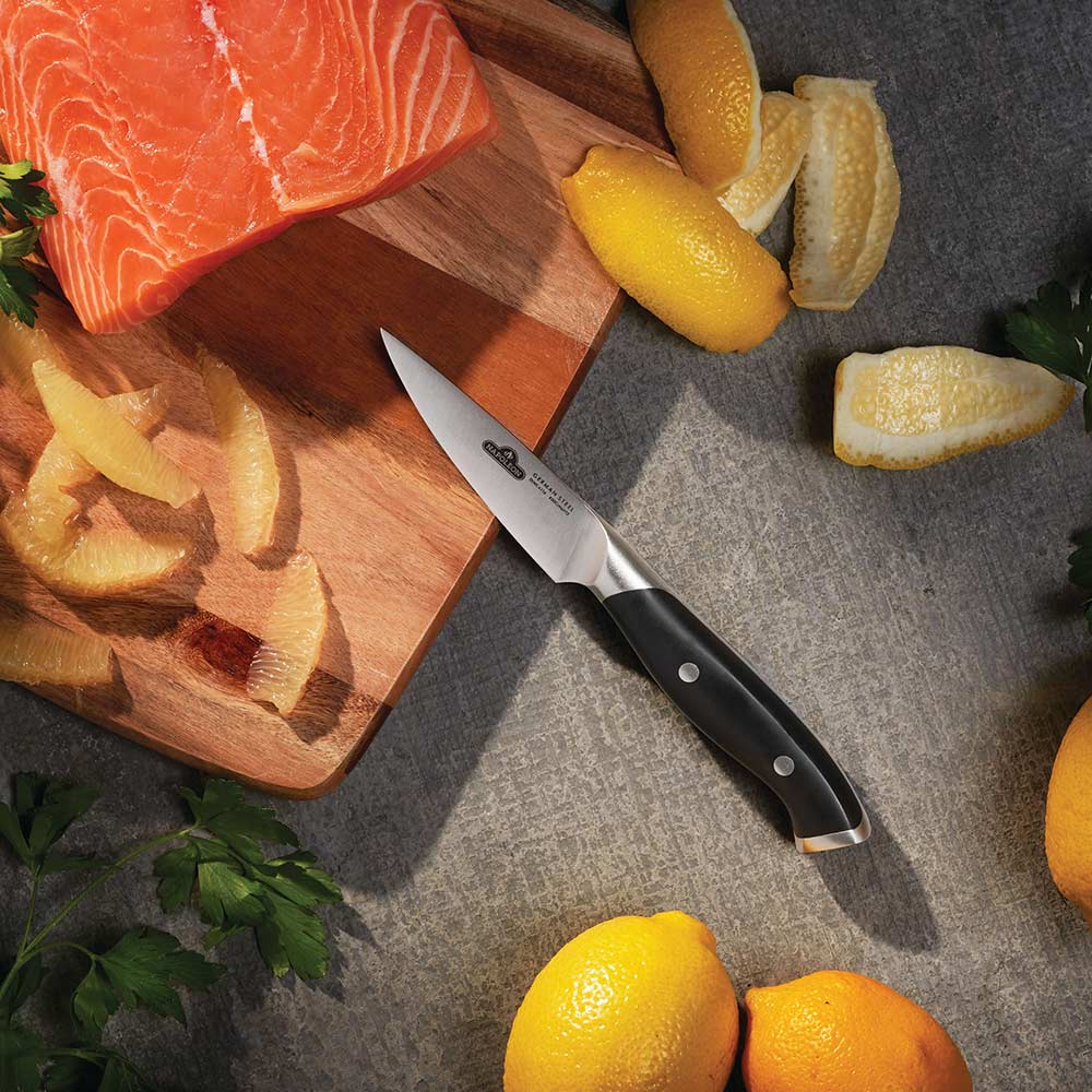 Paring knife with stainless blade and black handle, resting on cutting board