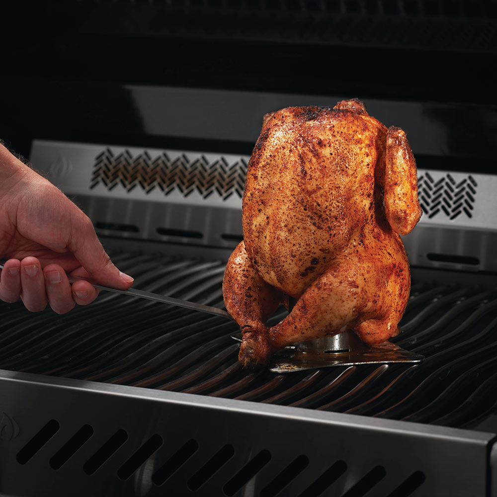 Chicken on stainless steel roaster stand on a grill grate