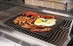 Cast iron reversible griddle on grill grate, topped with cooked food