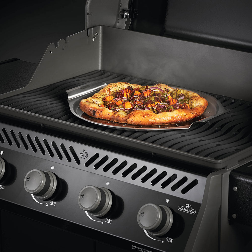 Stainless steel pizza pan holding a cooked pizza on a grill rack