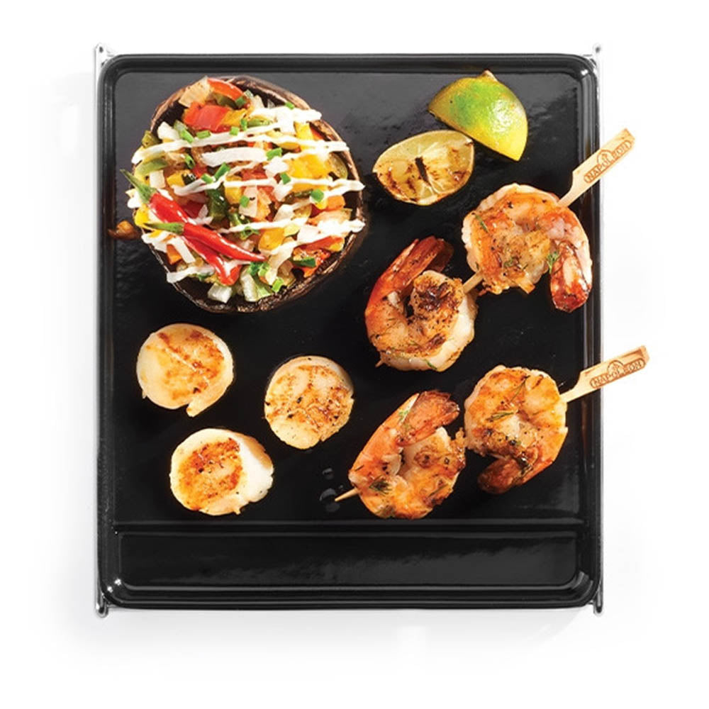 Cast iron griddle with grilled shrimp, scallops, and vegetables on black cooking surface