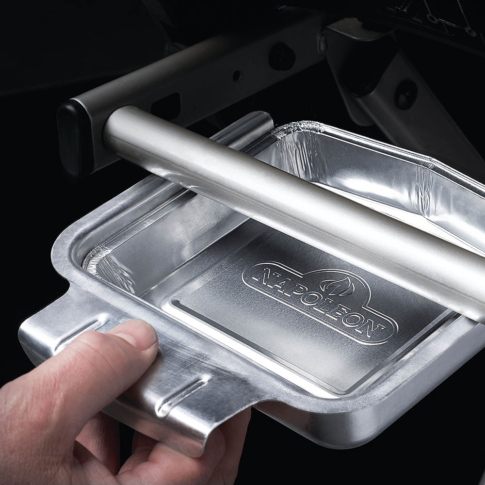 Napoleon aluminum grease tray placed in grill, shiny rectangular foil pan with logo