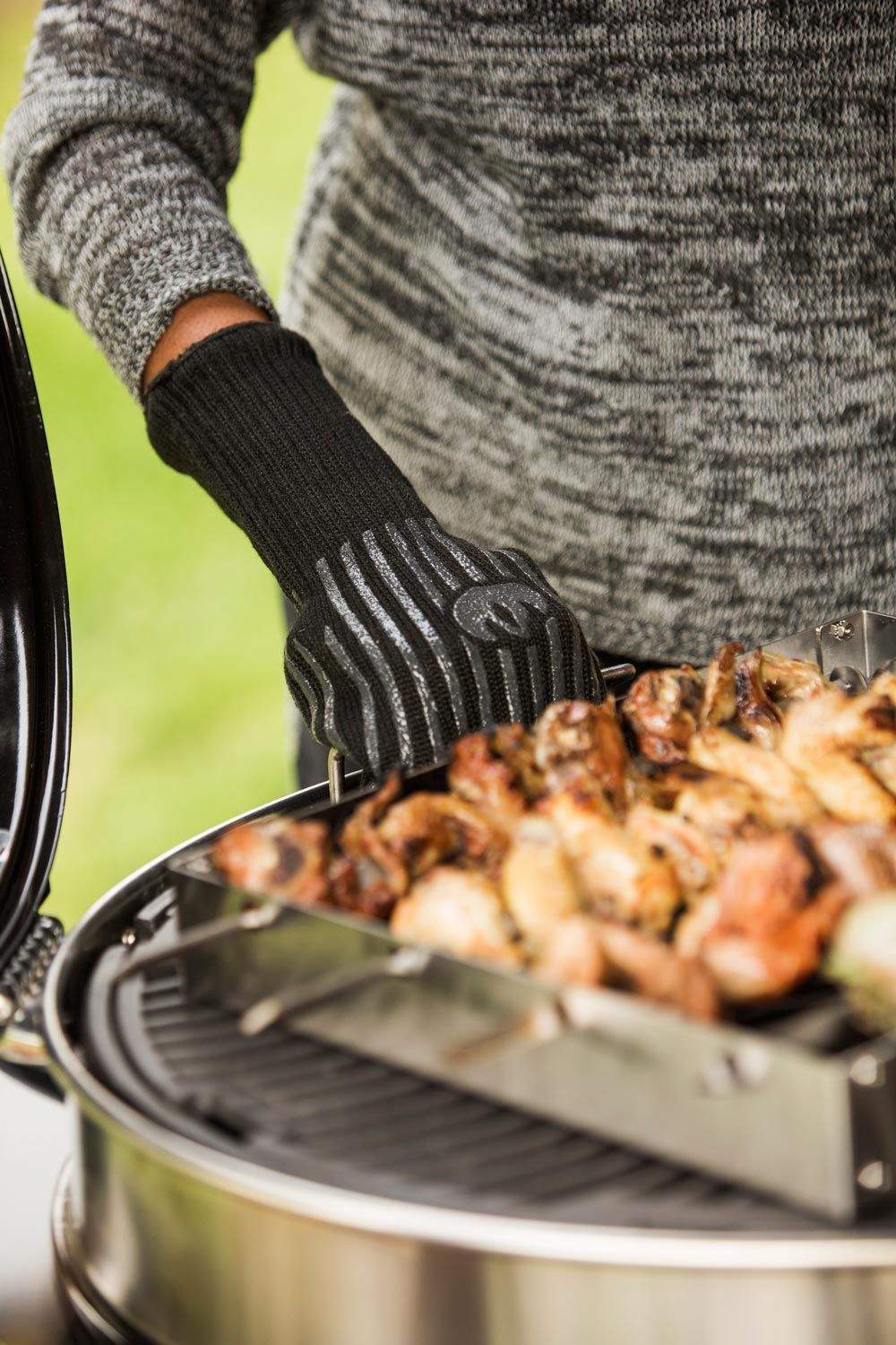Napoleon BBQ glove in black striped knit over a grill with cooked meat