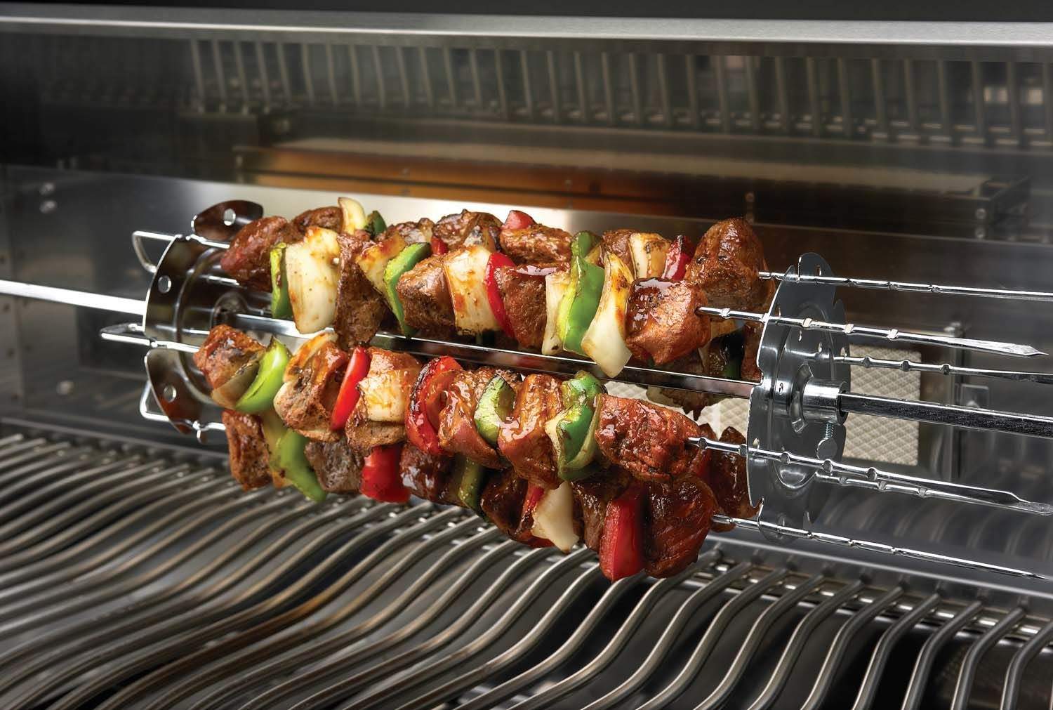 Rotisserie spit with vegetable and meat skewers roasting on grill grates.