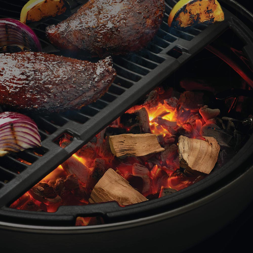 Grill with burning apple wood chunks and smoked meat slices