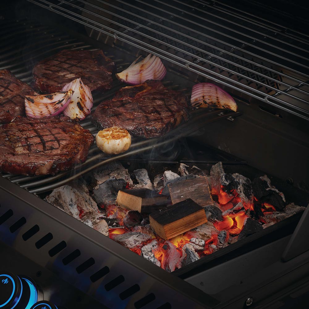 Whiskey barrel wood chunks on a grill grate, burning with visible flames