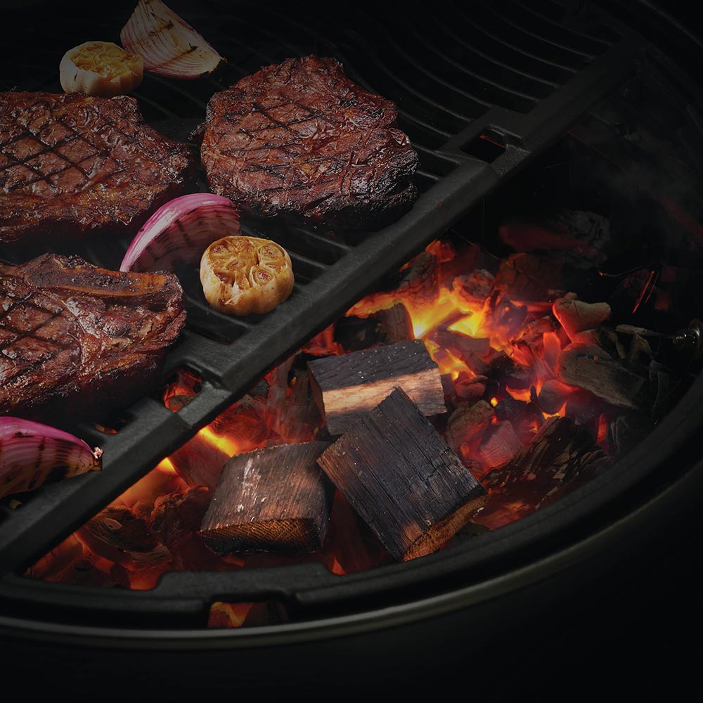 Whiskey barrel wood chunks on a grill grate, with glowing embers and flames