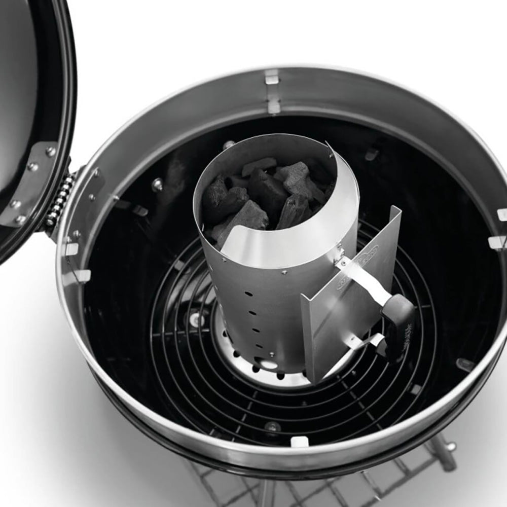 Charcoal chimney starter inside a grill, holding charcoal cubes in the metal chamber