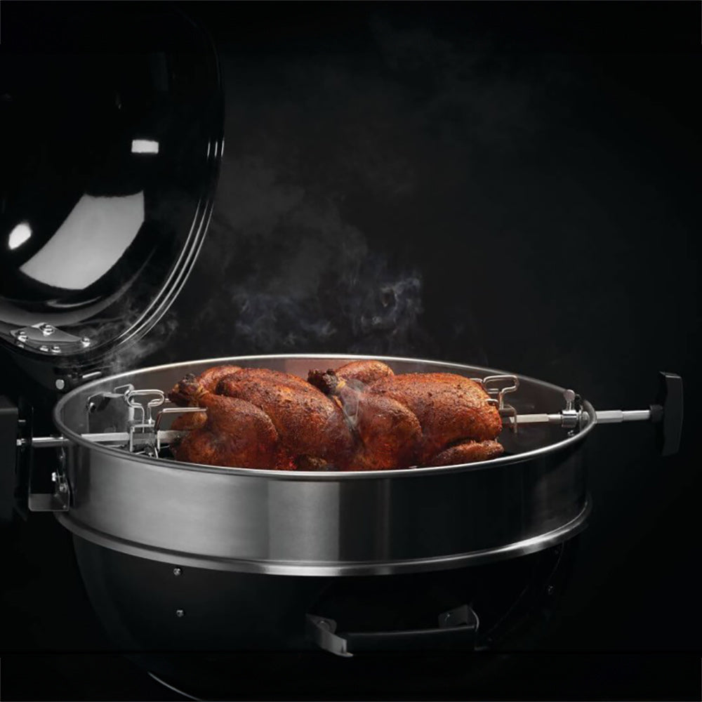 Rotisserie chicken on stainless spit rod for charcoal grill, secured with end forks