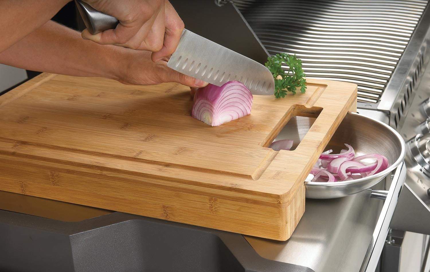 Wood carving and cutting board with inset stainless steel bowls, onion being sliced