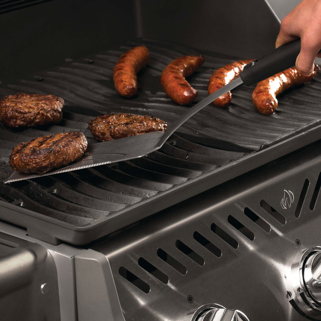 Grill tool set with spatula and fork used on BBQ grates with sausages