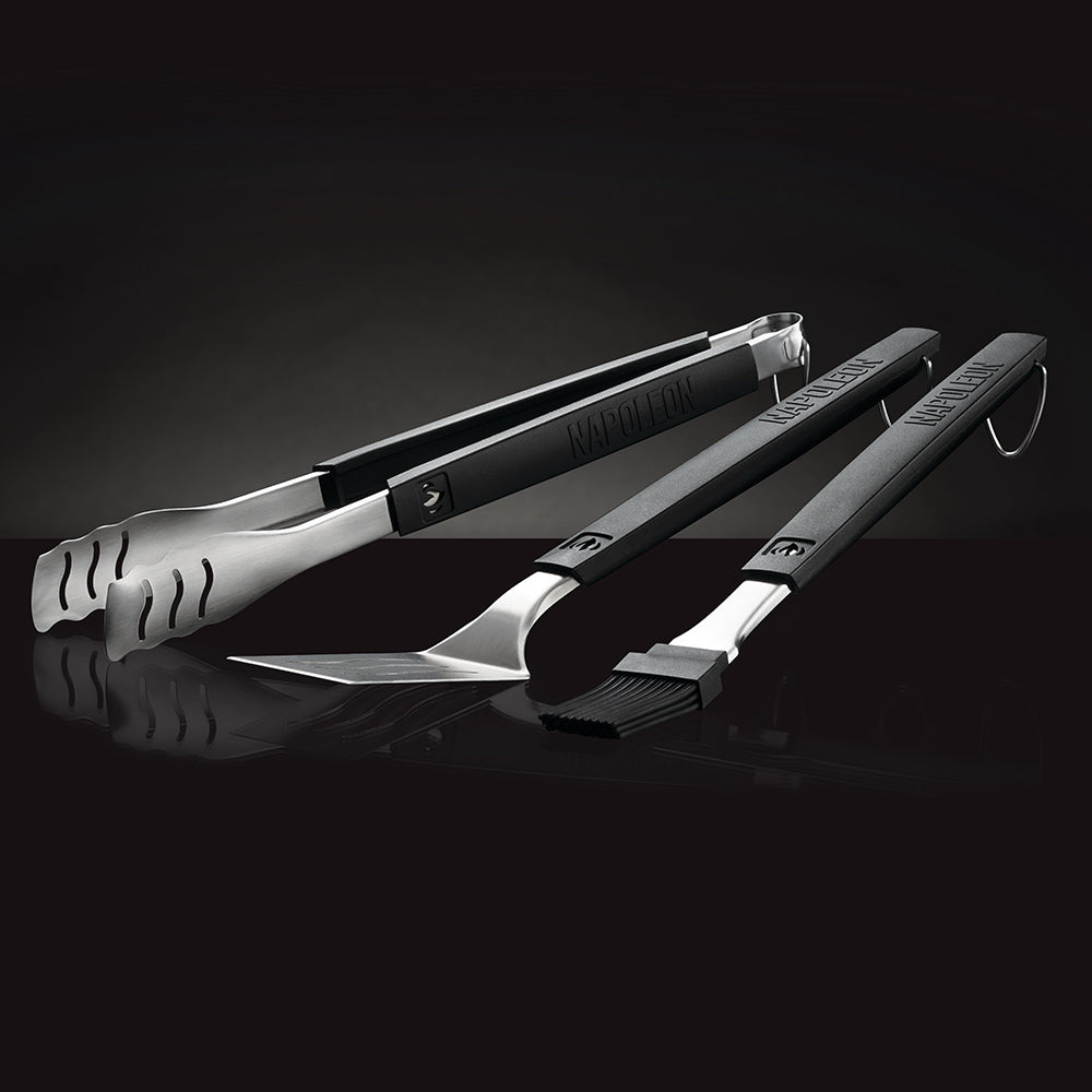 Three BBQ grilling tools with stainless heads and black handles, laid out for use
