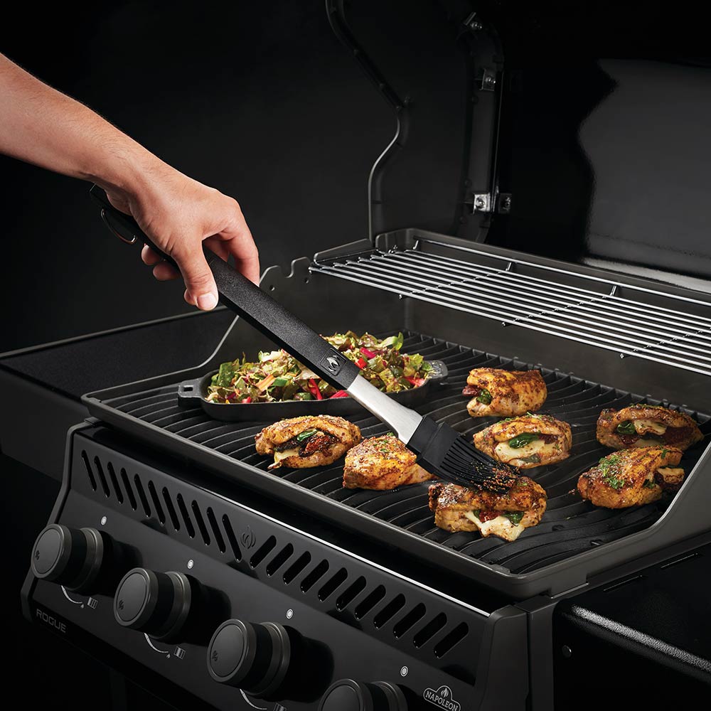 BBQ spatula turning grilled food on a grill, with tongs and slotted turner nearby