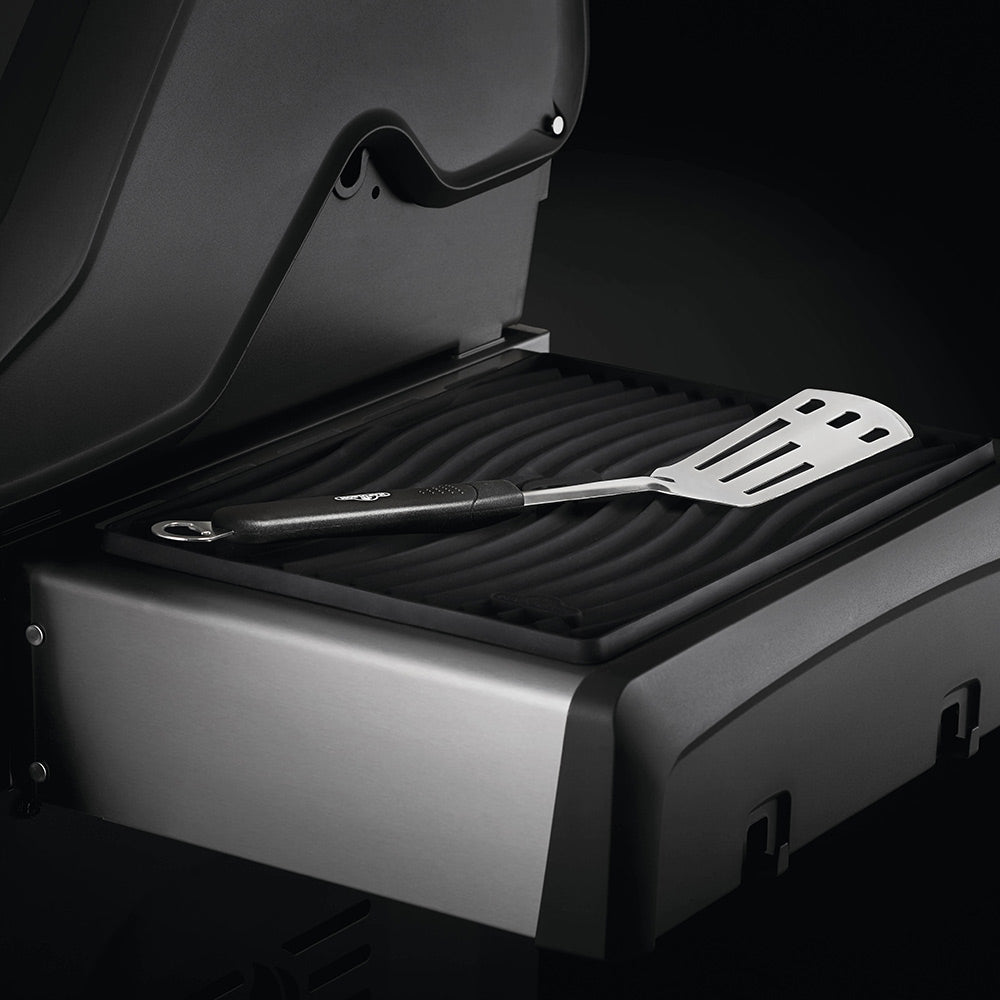 Black silicone side shelf mat with ridged grooves holding spatula and tongs