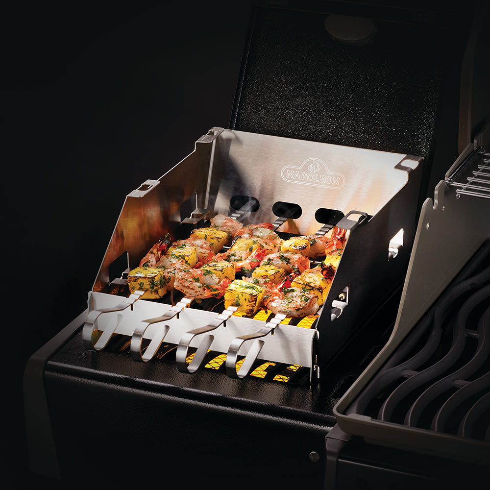 Metal skewer rack with side burner windshield over grilled vegetables and flames