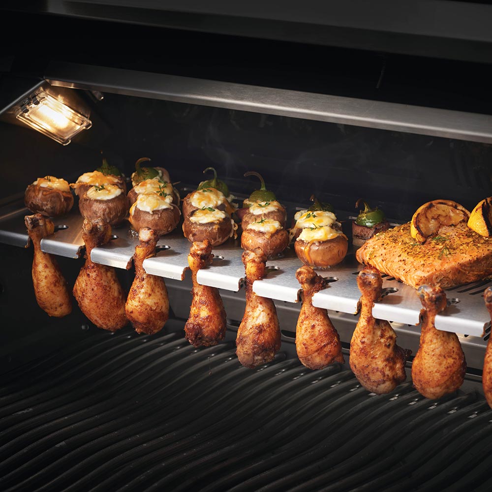 Grilling rack with roasted meat pieces on a grate inside the grill