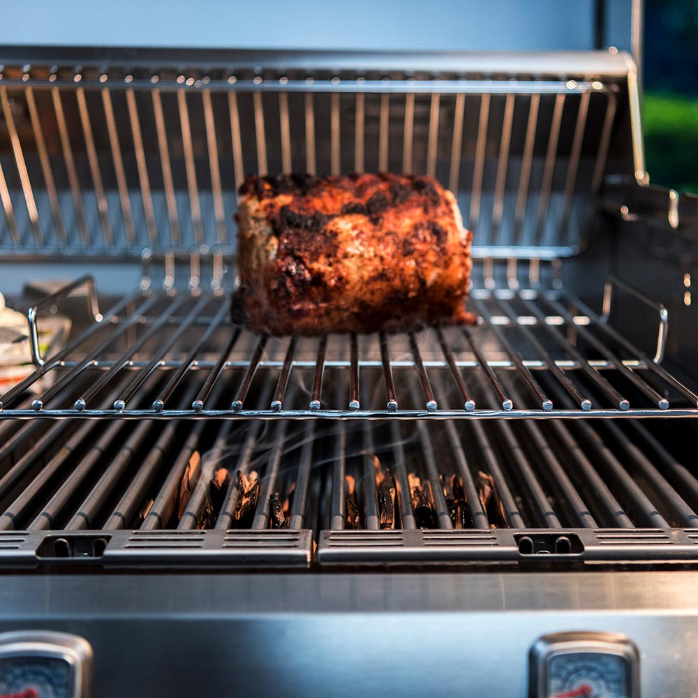 Wire roasting rack with chicken resting on grates inside barbecue