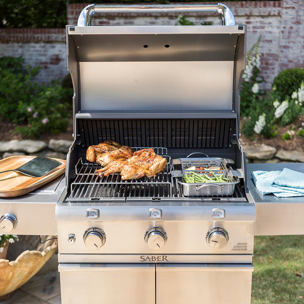 Open outdoor grill with wire roasting rack insert and cooked meat and greens