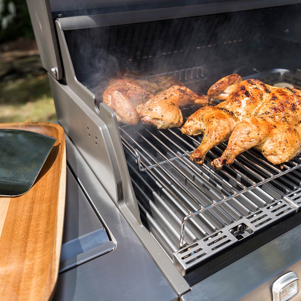 Wire roasting rack in grill holding seasoned chicken, side view