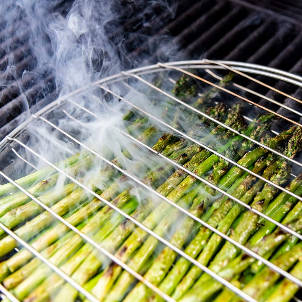 Grill basket filled with green vegetables, steam rising