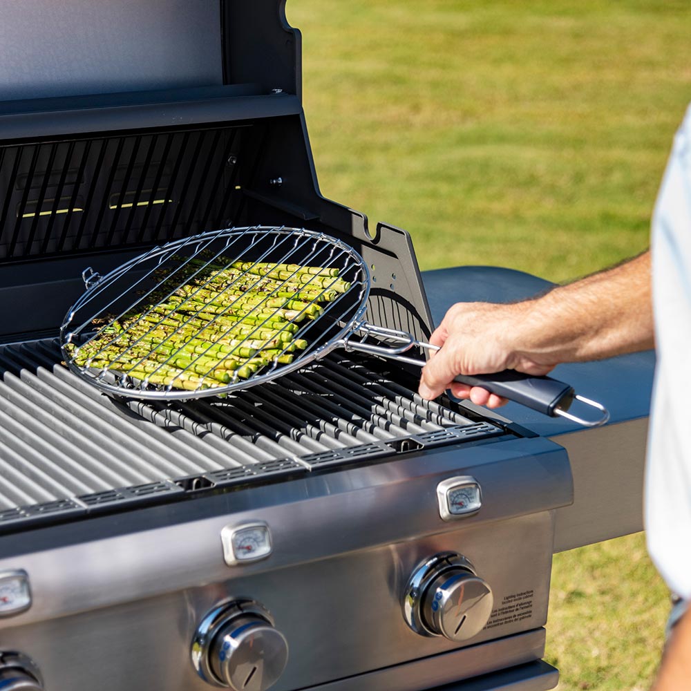 Wire grill basket set on grill grates with vegetables inside