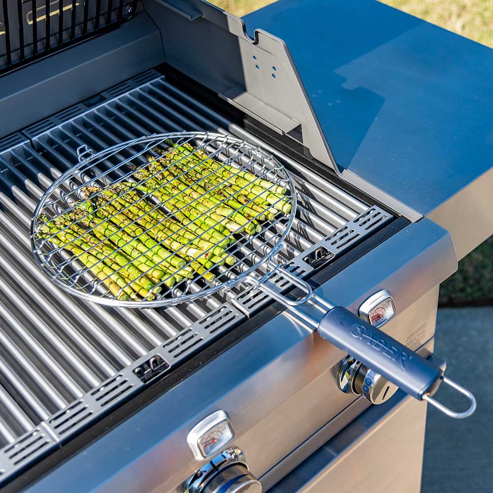 Round wire grill basket on grill grates with vegetables inside