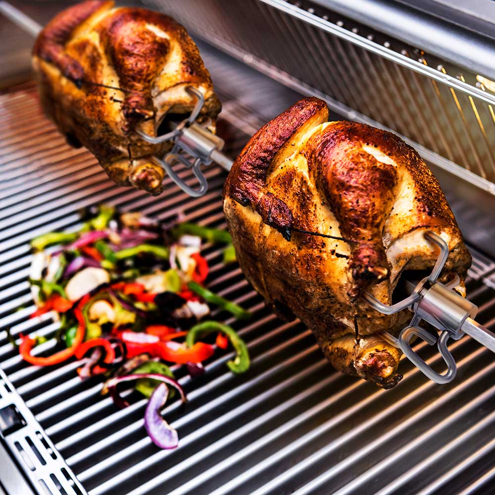 Rotisserie fork holding cooked chicken with secure U-shaped clips