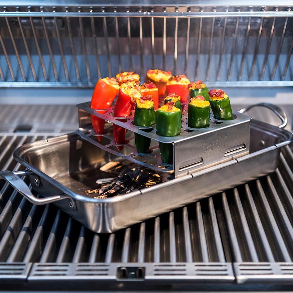Double pepper roaster on grill, holding green and red stuffed peppers