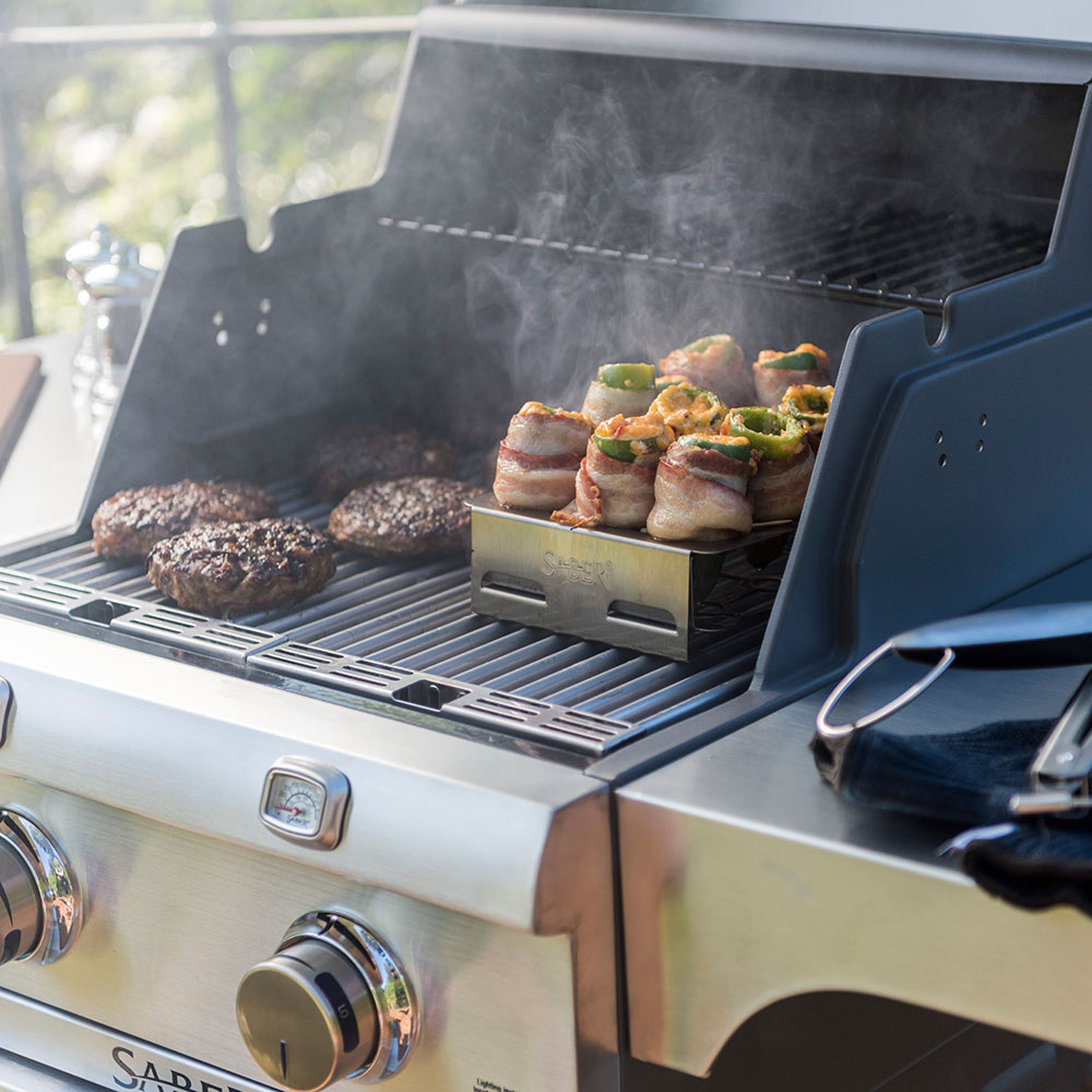 Side view of double pepper roaster holding stuffed peppers on grill grates
