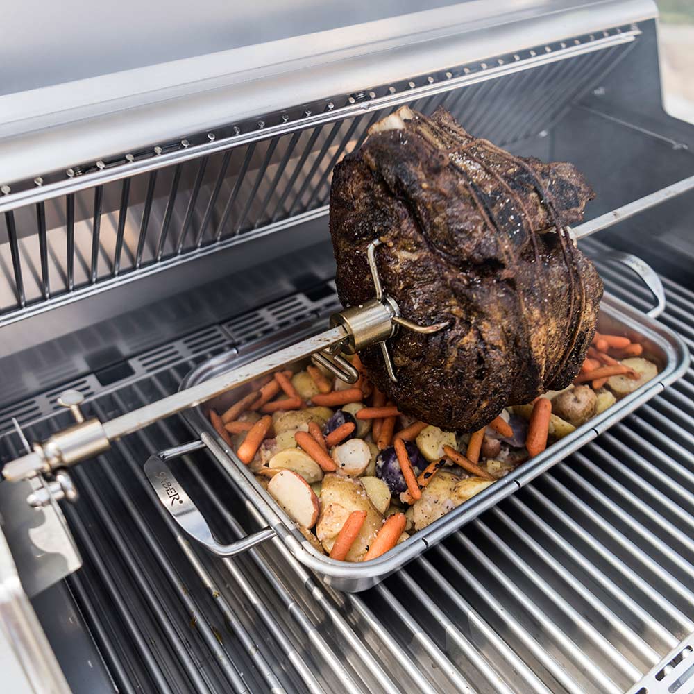 Rotisserie grill set with seasoned chicken rotating on spit over burner tray