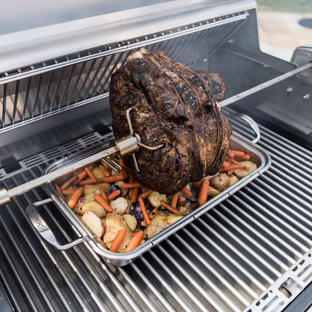 Rotisserie rod and spit with whole chicken above grill pan