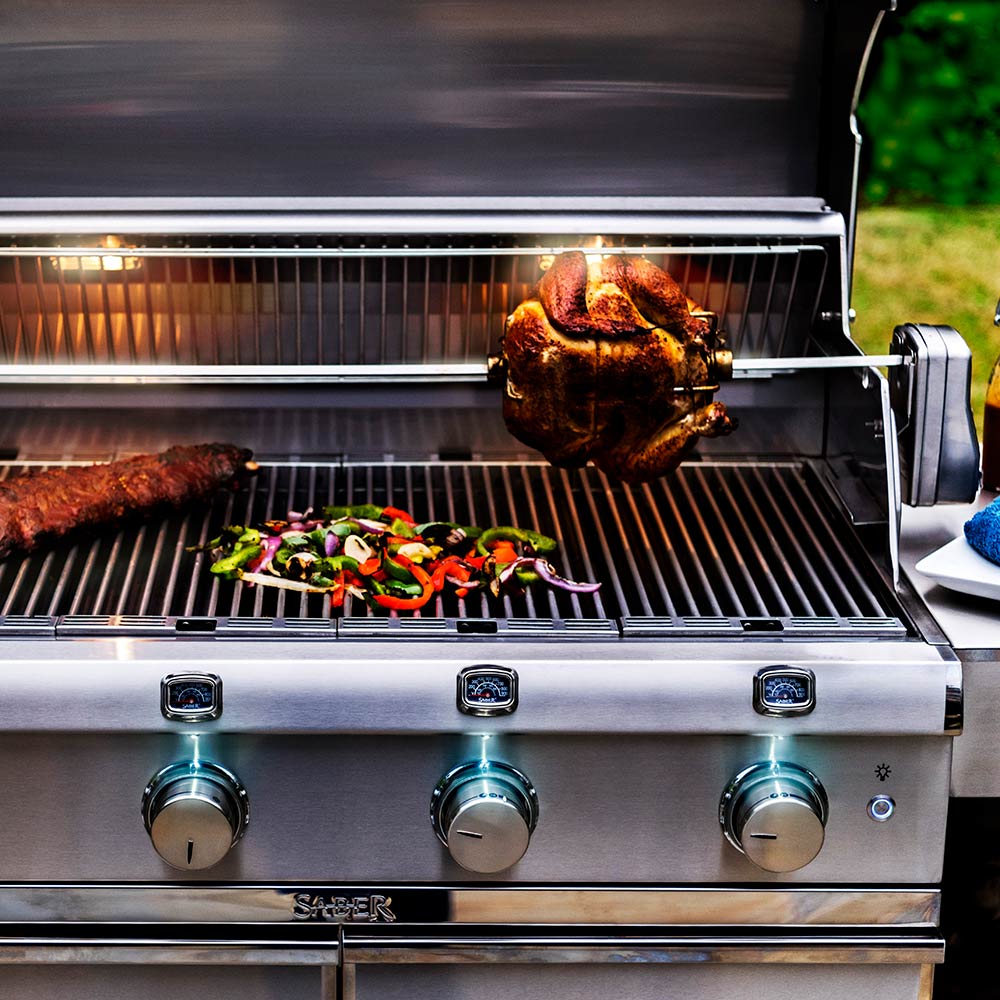 Rotisserie chicken roasting on stainless steel spit over grill grates