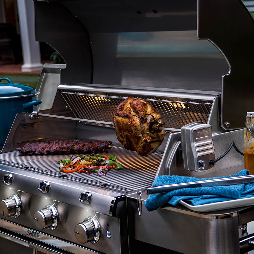 Rotisserie chicken on grill spit with vegetable tray and side handle
