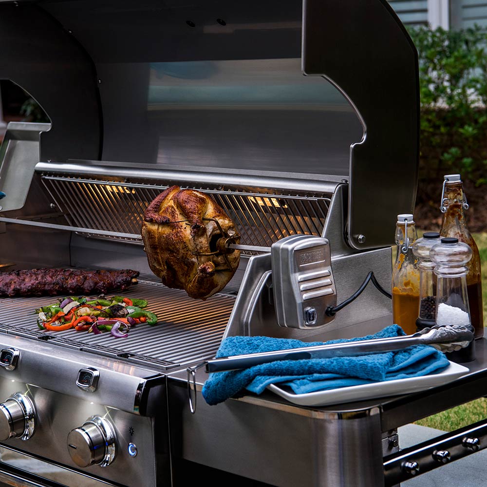 Stainless steel rotisserie rod with chicken in open grill