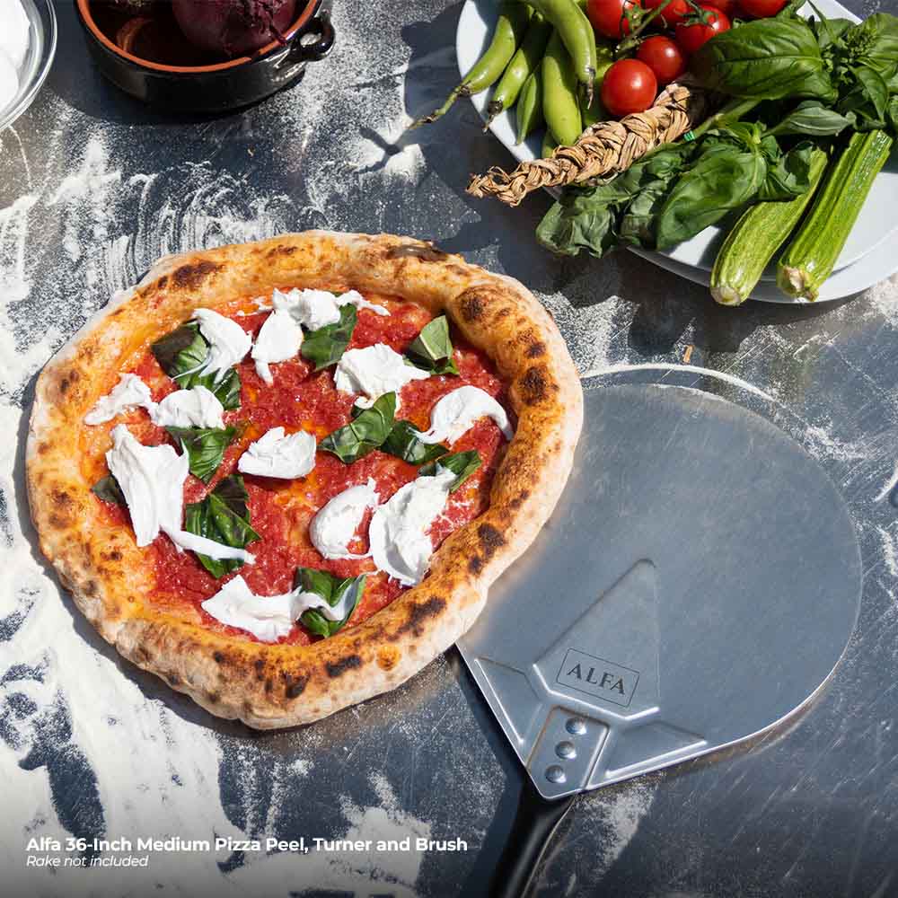 Pizza peel and turner with topped pizza and fresh herbs on pizza stone