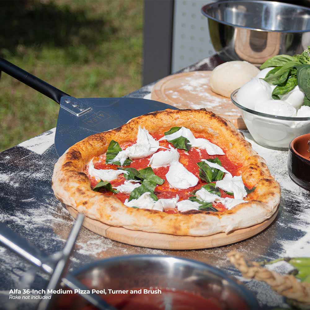Pizza turner and perforated pizza peel beside topped pizza on a board