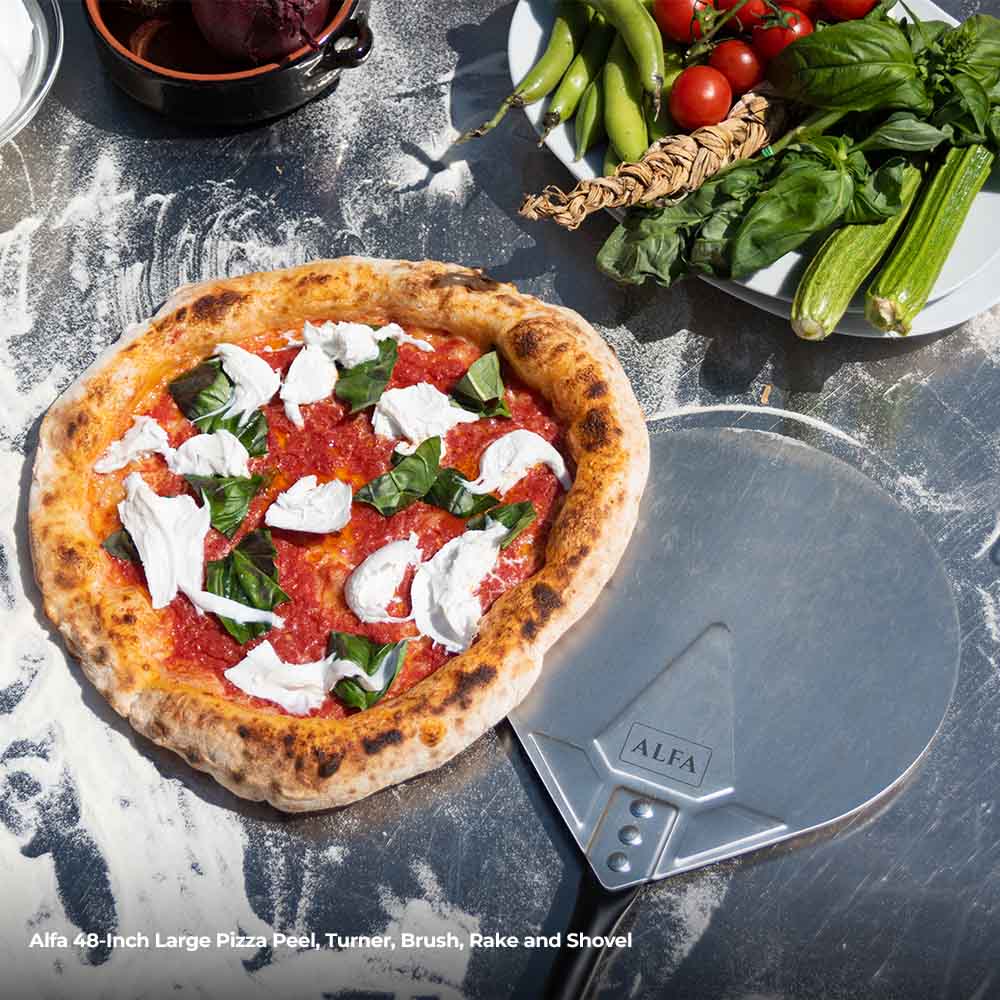 Topped pizza on a round pizza peel with a metal turner