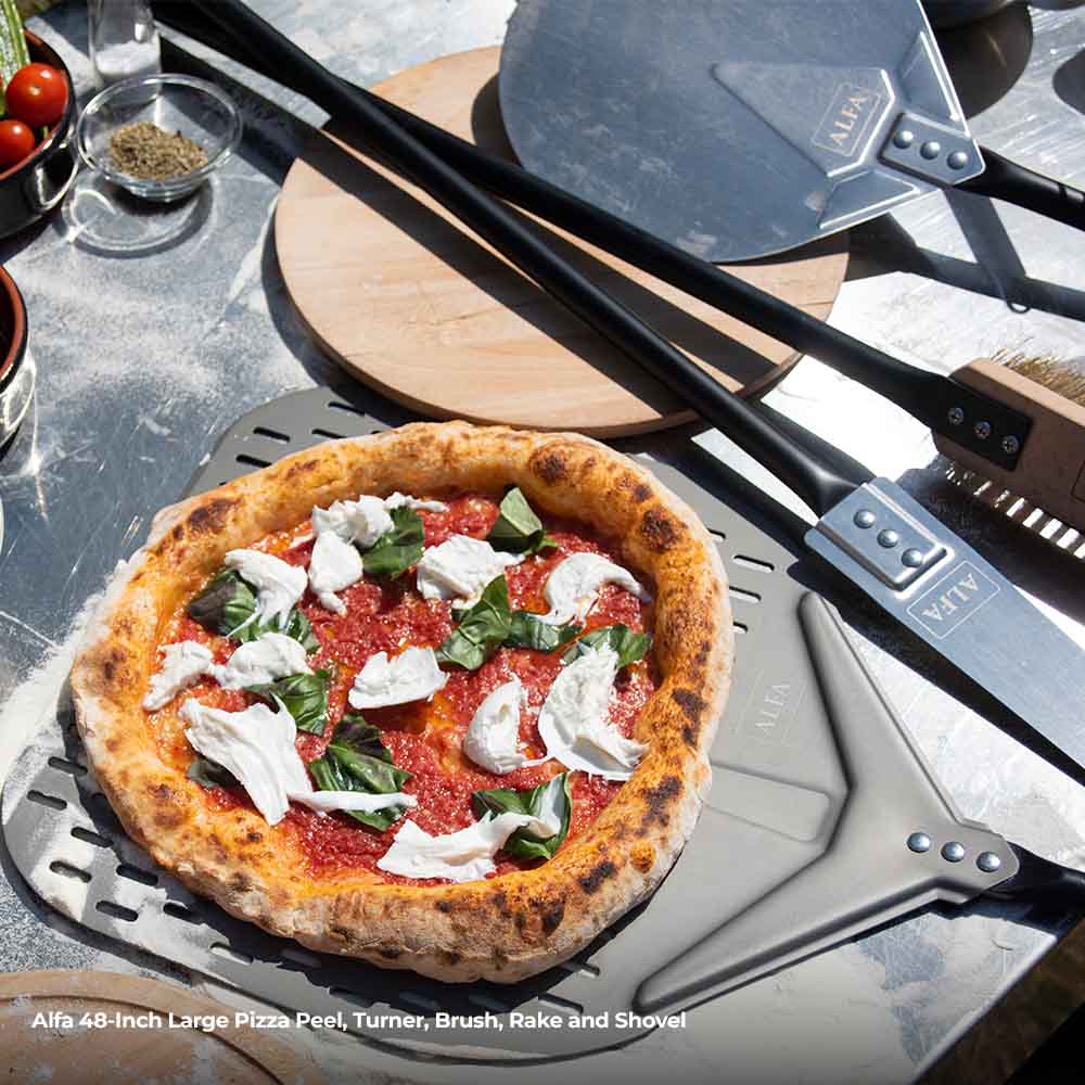 Topped pizza on perforated peel with rake and shovel tools