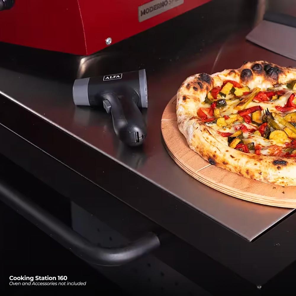 ALFA pizza on a wooden board beside a red domed oven opening