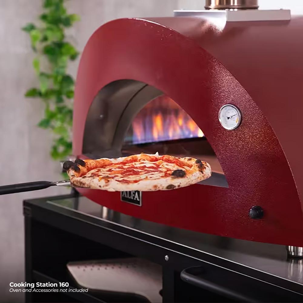 Red domed pizza oven with pizza on stone and visible flame