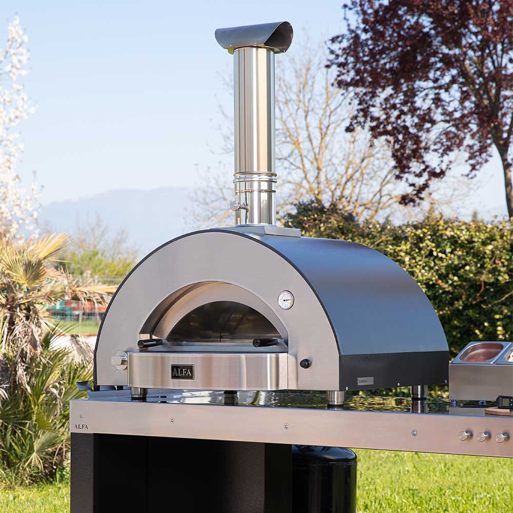 Outdoor stainless steel pizza oven with rounded dome and chimney flue