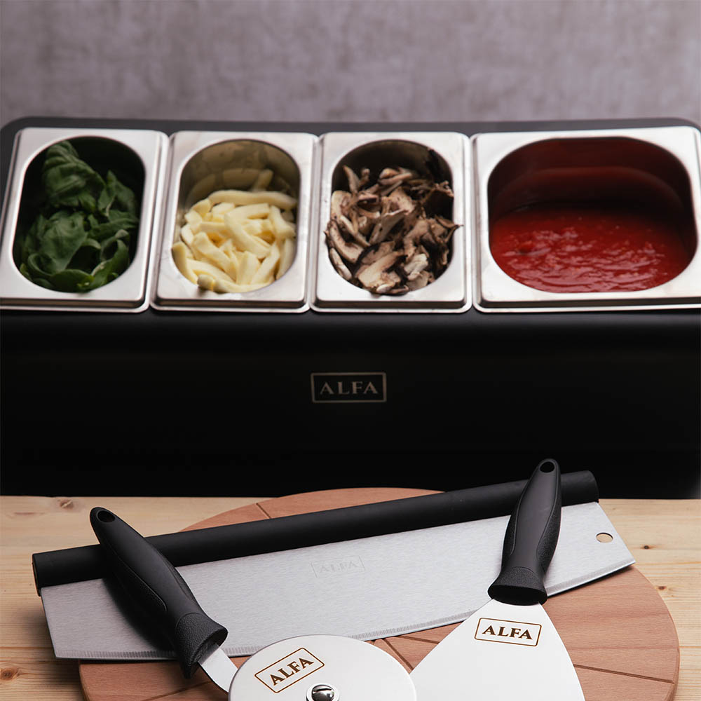 Countertop topping station with four ingredient bowls: greens, onions, mushrooms, and red sauce