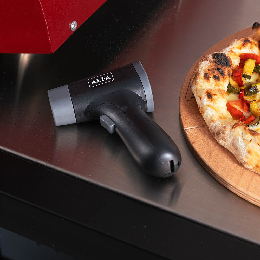 Handheld black laser thermometer with trigger head, resting on oven front