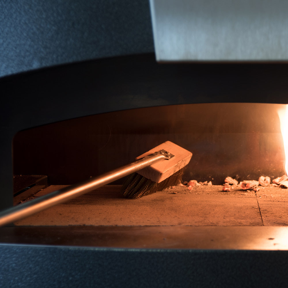 Pizza oven interior with Alfa hybrid kit tool near glowing coals and ash