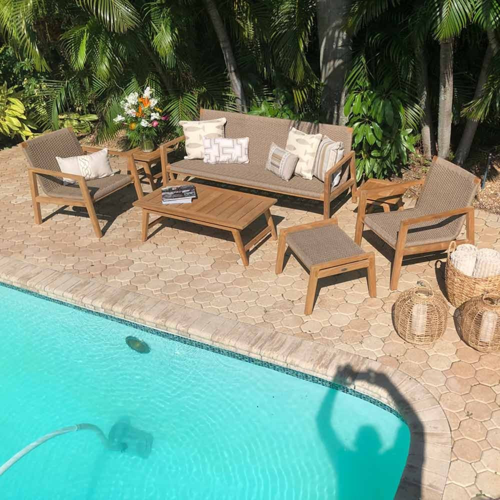 Poolside patio seating set with light wood frames and tan cushions, plus rectangular coffee table